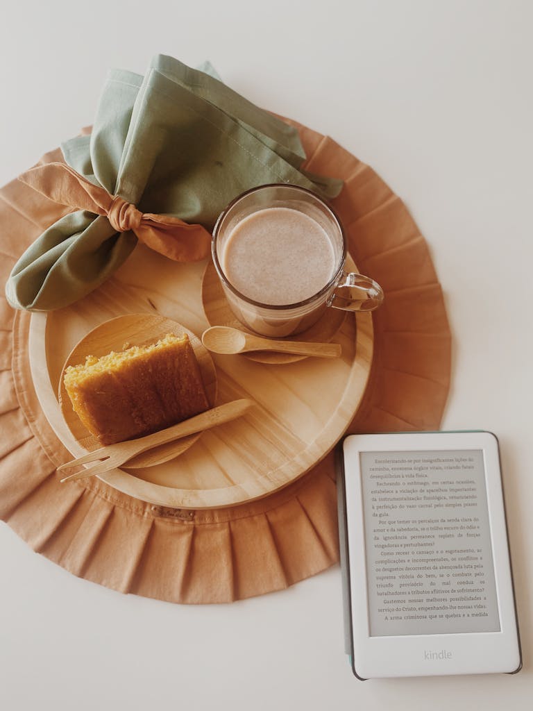 Warm breakfast setting with a slice of cake, hot drink, and eReader in São Paulo, Brazil.